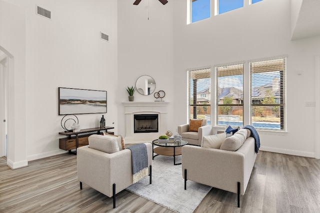 living room featuring a towering ceiling, ceiling fan, and light hardwood / wood-style floors