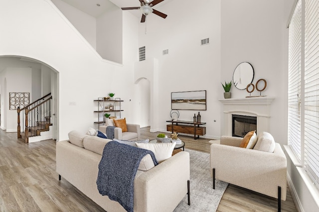 living room with ceiling fan, a towering ceiling, and wood-type flooring