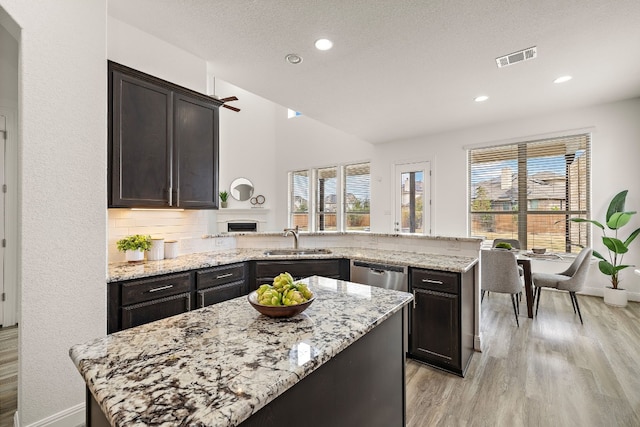 kitchen with a healthy amount of sunlight, light stone countertops, and sink