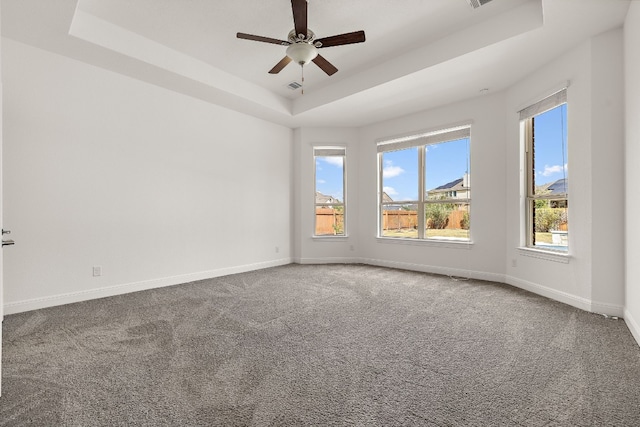 carpeted empty room featuring ceiling fan and a raised ceiling