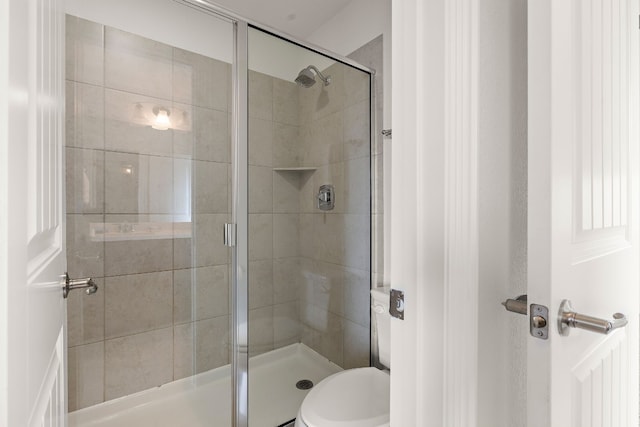 bathroom featuring toilet and a shower with shower door