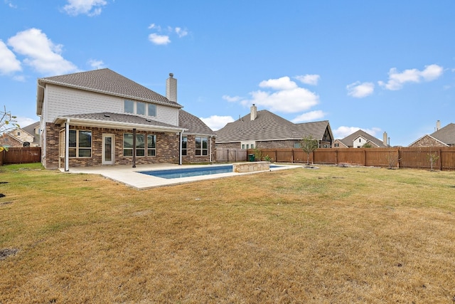 rear view of house featuring a patio, a lawn, and a fenced in pool