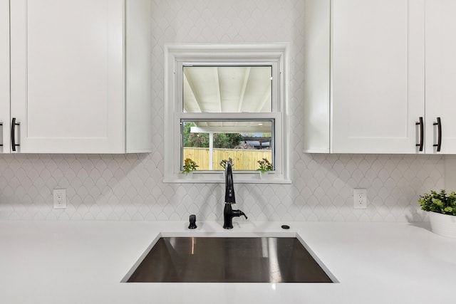 kitchen with white cabinetry, decorative backsplash, and sink