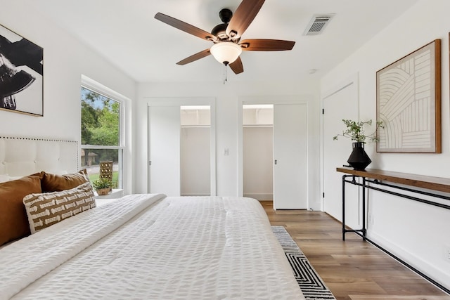 bedroom featuring a spacious closet, a closet, light wood-type flooring, and ceiling fan