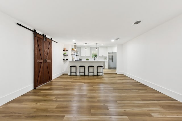 kitchen with a kitchen bar, stainless steel fridge, light hardwood / wood-style flooring, and hanging light fixtures