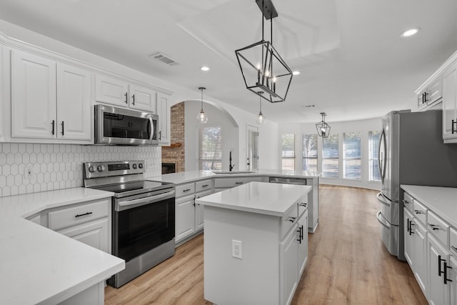 kitchen featuring white cabinetry, stainless steel appliances, decorative light fixtures, and sink