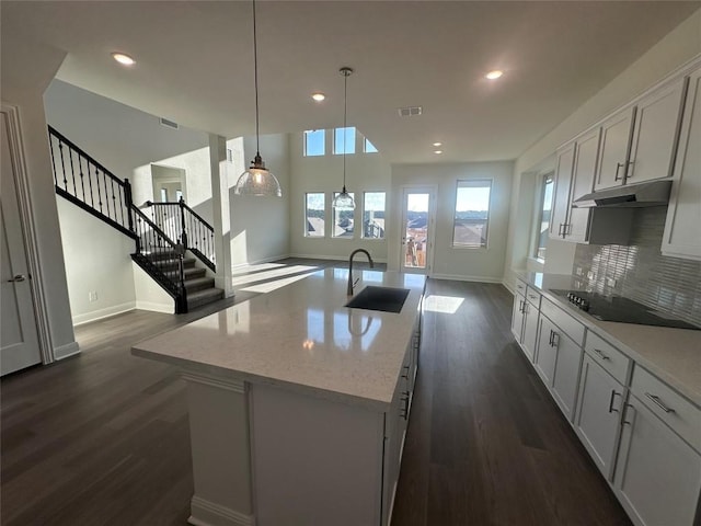 kitchen with pendant lighting, a center island with sink, white cabinetry, and sink