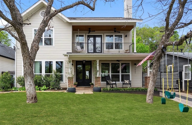 view of front of home with ceiling fan, a front yard, and a balcony