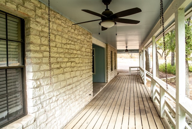 wooden terrace featuring covered porch and ceiling fan