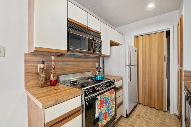 kitchen with white cabinetry, white fridge, a textured ceiling, and stainless steel stove