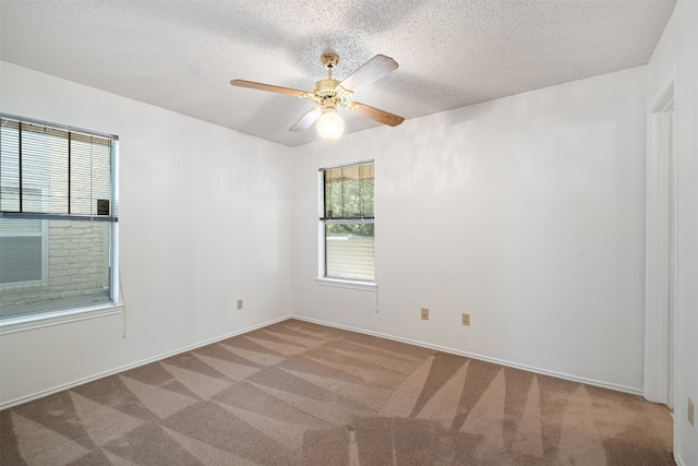 carpeted empty room featuring a textured ceiling, a healthy amount of sunlight, and ceiling fan