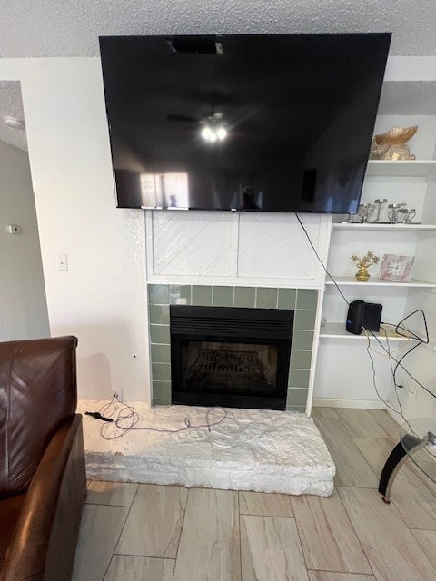 interior details with a textured ceiling and a tiled fireplace