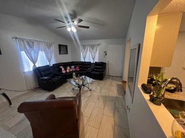 living room with a textured ceiling, ceiling fan, and vaulted ceiling