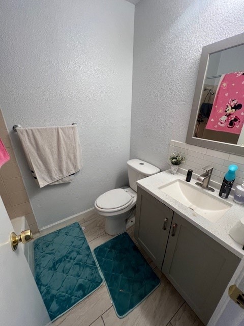 bathroom featuring vanity, decorative backsplash, toilet, and walk in shower