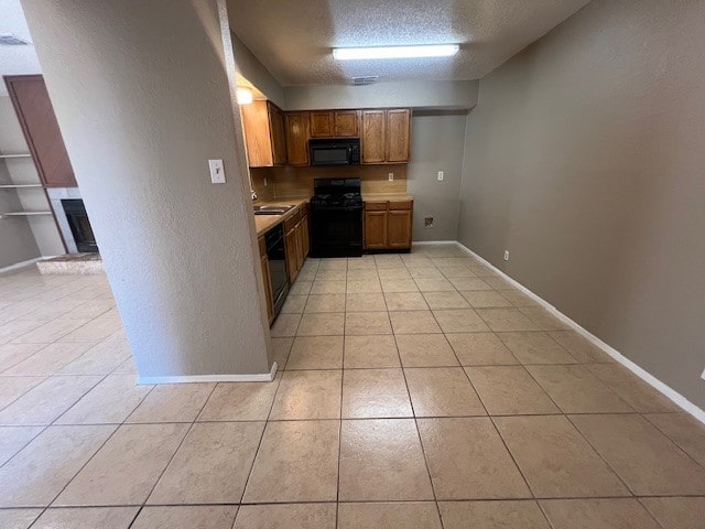 kitchen with sink, black appliances, light tile patterned flooring, and a textured ceiling