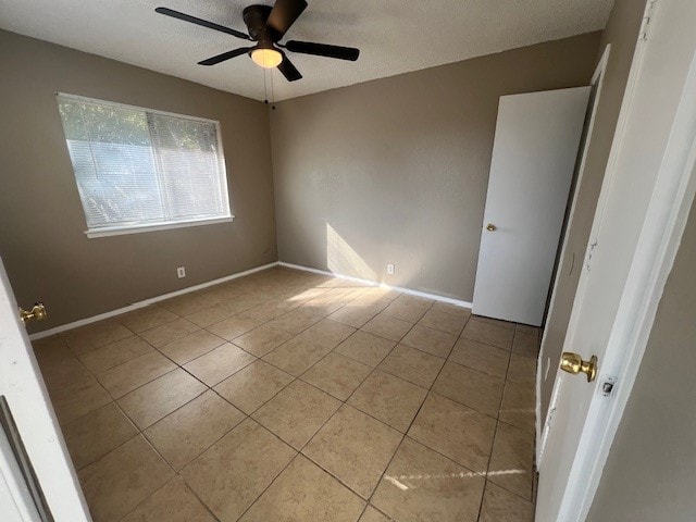 unfurnished room with a textured ceiling, light tile patterned floors, and ceiling fan