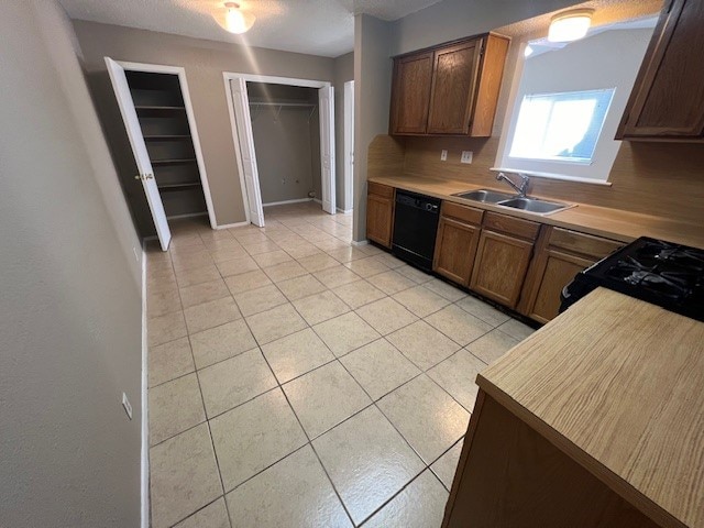 kitchen with light tile patterned flooring, black appliances, sink, and a textured ceiling