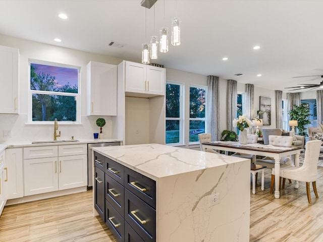 kitchen with white cabinets, hanging light fixtures, light hardwood / wood-style flooring, sink, and a center island