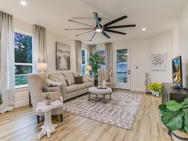 living room featuring ceiling fan, plenty of natural light, and light wood-type flooring