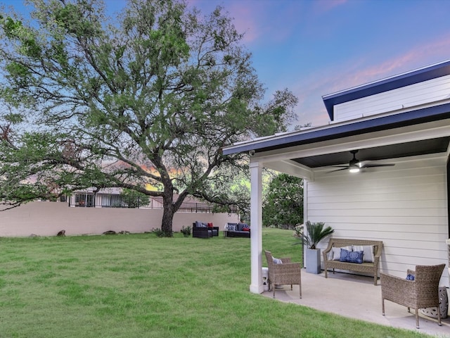 yard at dusk featuring a patio area and ceiling fan