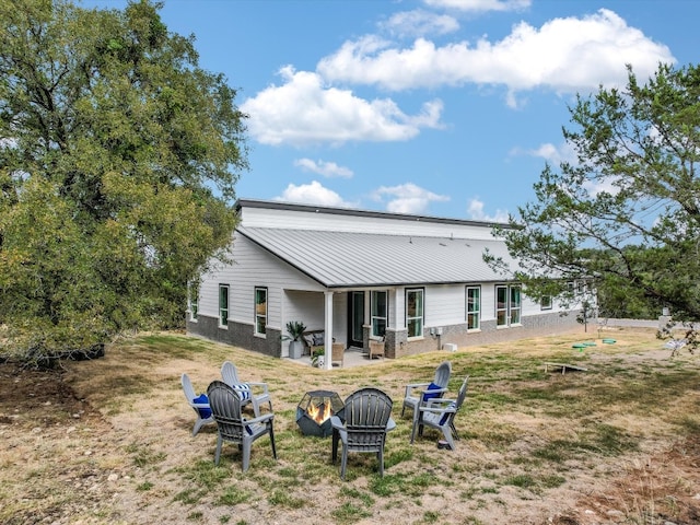 back of house with an outdoor fire pit and a patio