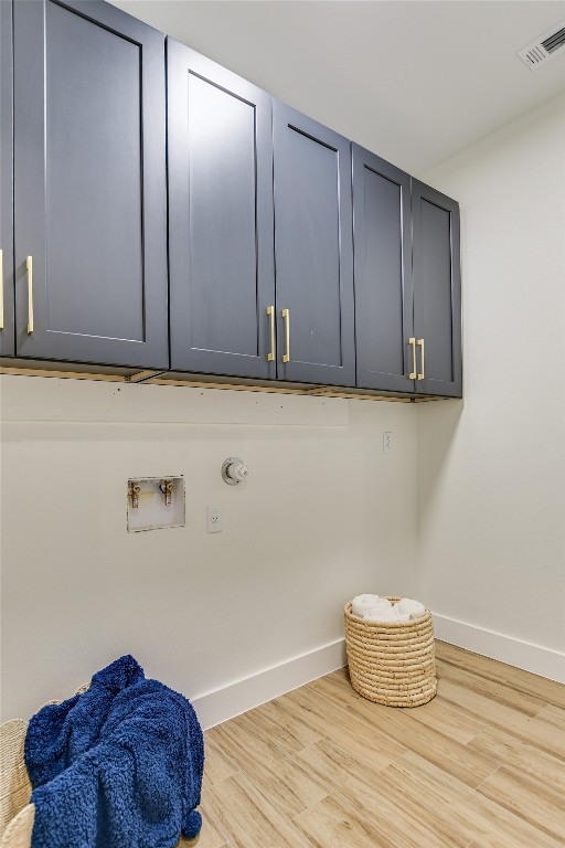 clothes washing area featuring hookup for a washing machine, gas dryer hookup, light hardwood / wood-style floors, and cabinets