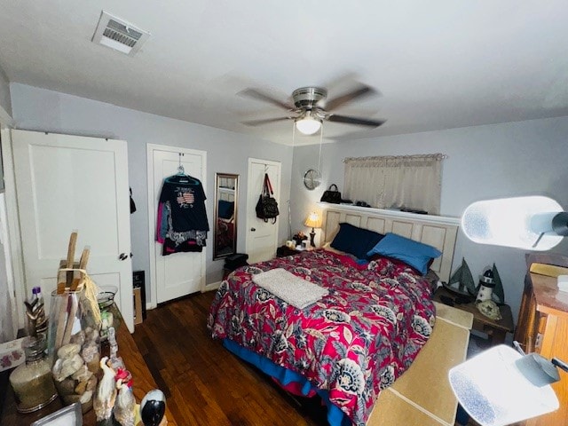 bedroom featuring dark hardwood / wood-style flooring, two closets, and ceiling fan