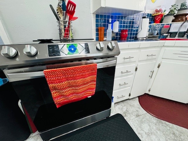 kitchen featuring white cabinetry, backsplash, stainless steel electric range, and tile counters