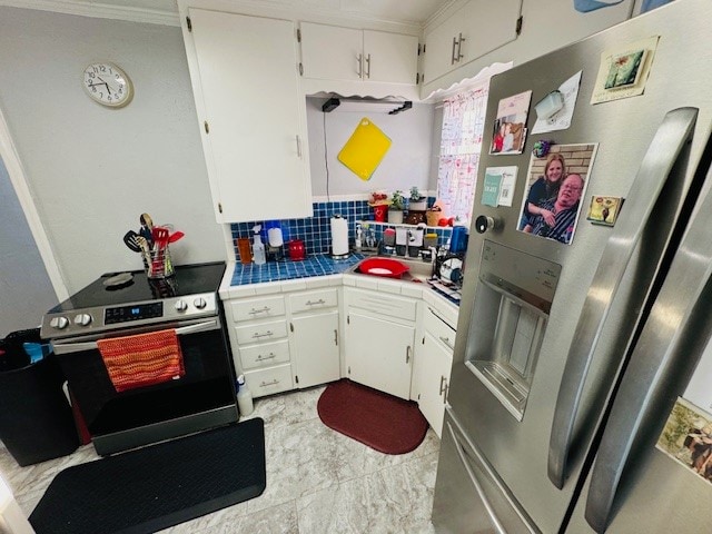 kitchen with tile countertops, appliances with stainless steel finishes, white cabinets, and tasteful backsplash