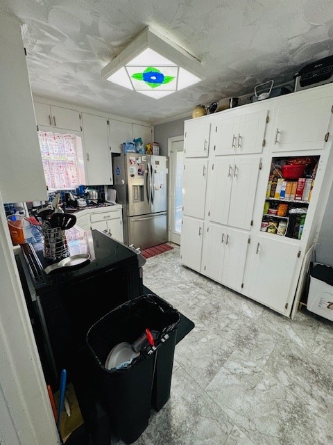 kitchen featuring white cabinetry and stainless steel refrigerator with ice dispenser