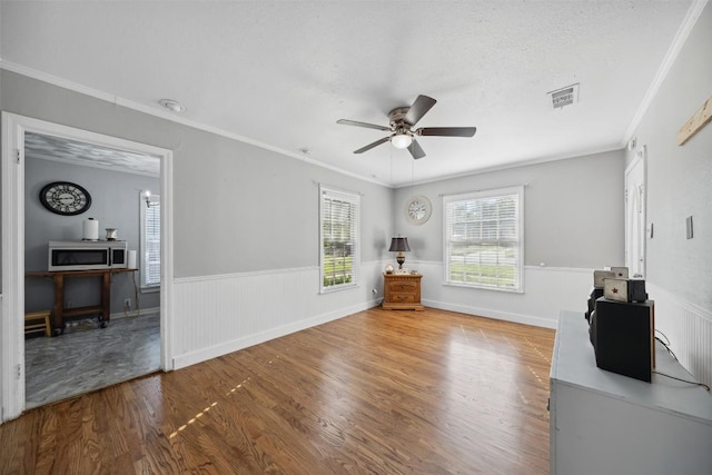 1514 S 13th St, Temple, TX 76504 - living room featuring wood finished floors, ceiling fan, a wainscoted wall, and ornamental molding