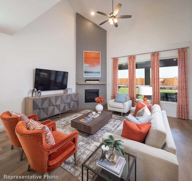 living room featuring hardwood / wood-style floors, high vaulted ceiling, a fireplace, and ceiling fan