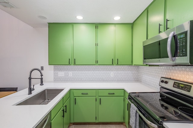 kitchen featuring sink, tasteful backsplash, light tile patterned floors, appliances with stainless steel finishes, and green cabinets