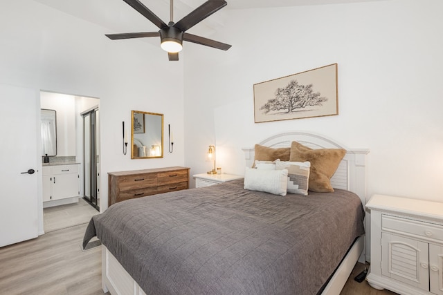 bedroom featuring ceiling fan, ensuite bathroom, light hardwood / wood-style floors, and a high ceiling