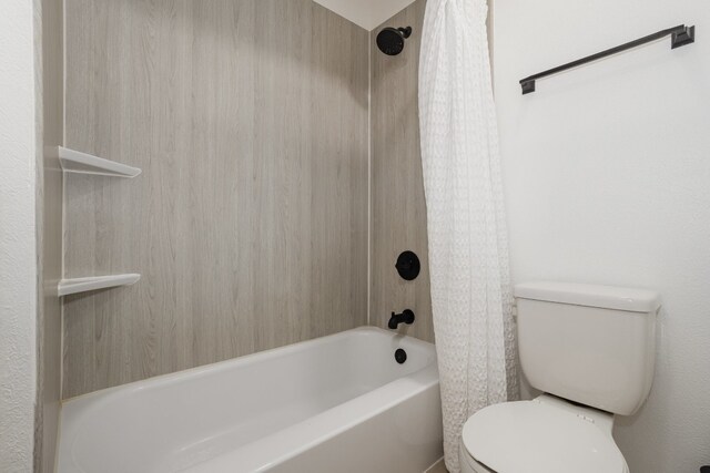 bathroom featuring shower / bathtub combination with curtain and toilet