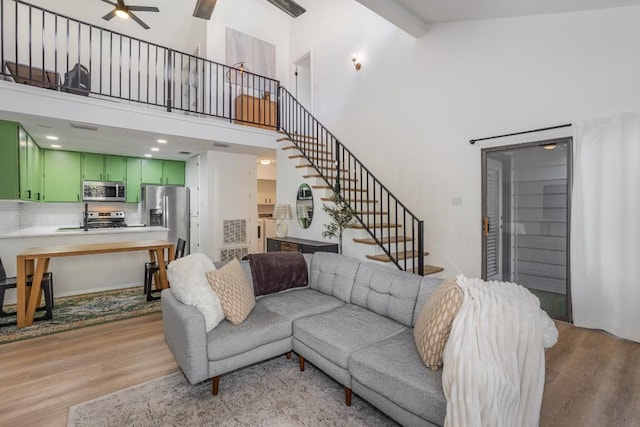 living room featuring high vaulted ceiling, beamed ceiling, sink, ceiling fan, and light wood-type flooring