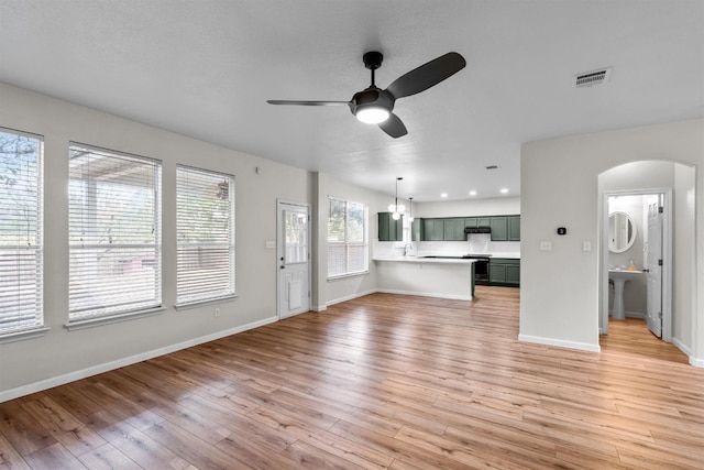 unfurnished living room with light hardwood / wood-style flooring, ceiling fan, sink, and a wealth of natural light