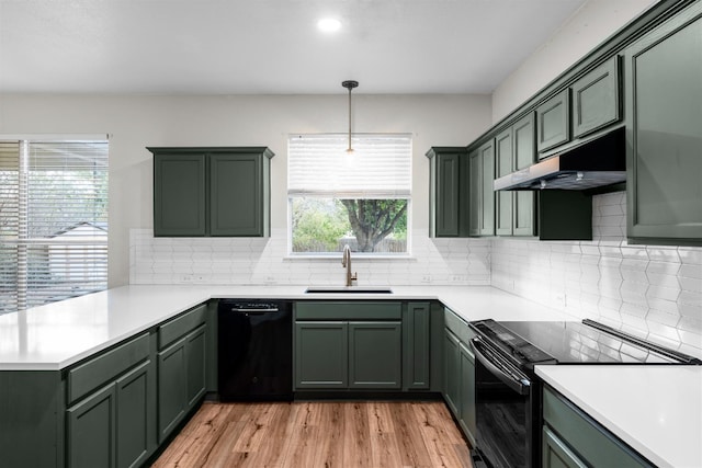 kitchen featuring kitchen peninsula, sink, black appliances, pendant lighting, and light wood-type flooring