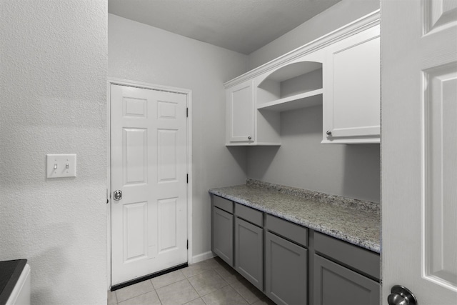 kitchen with light tile patterned flooring, white cabinetry, light stone counters, and gray cabinetry