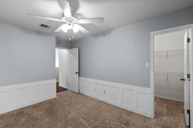 unfurnished bedroom with a closet, dark carpet, and ceiling fan