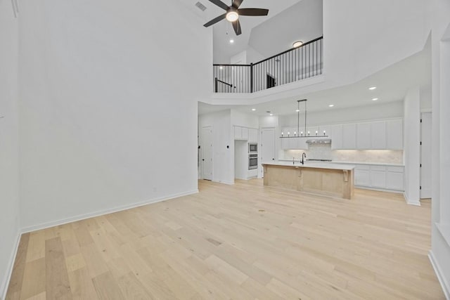 unfurnished living room featuring sink, ceiling fan, and light hardwood / wood-style floors