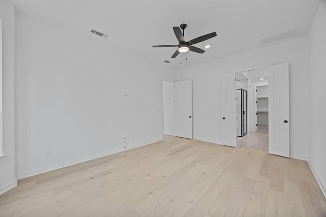 unfurnished bedroom with light hardwood / wood-style floors, a walk in closet, and ceiling fan