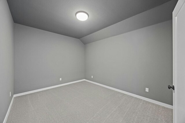 unfurnished room with lofted ceiling and carpet flooring