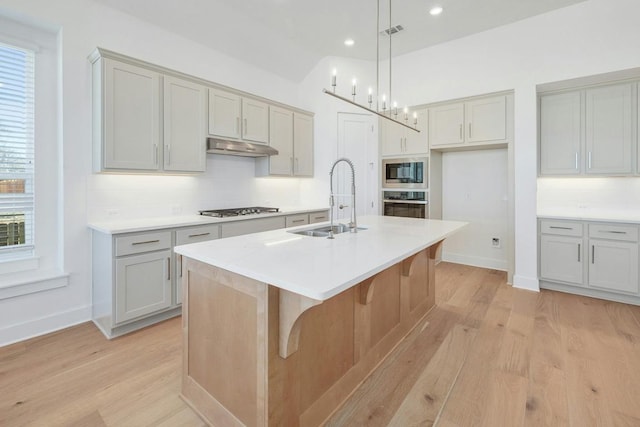 kitchen with a sink, appliances with stainless steel finishes, light wood finished floors, tasteful backsplash, and recessed lighting