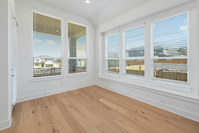 unfurnished sunroom featuring wood finished floors, baseboards, vaulted ceiling, and recessed lighting