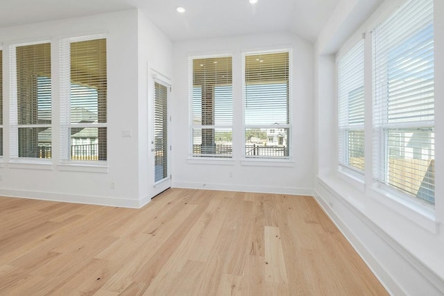 unfurnished sunroom featuring wood finished floors, plenty of natural light, baseboards, recessed lighting, and lofted ceiling