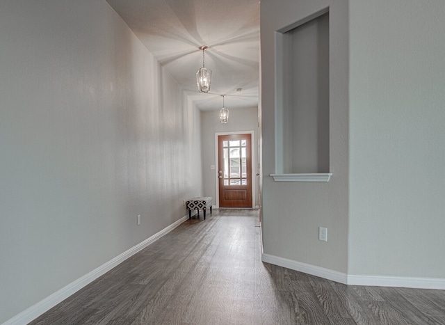 foyer with a chandelier, dark wood-style floors, and baseboards