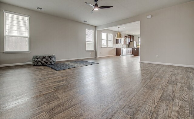 unfurnished living room with visible vents, baseboards, a ceiling fan, and wood finished floors