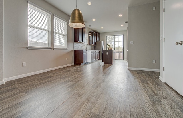 kitchen with wood finished floors, freestanding refrigerator, dark brown cabinets, decorative light fixtures, and open floor plan