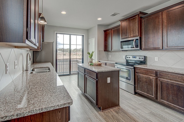 kitchen featuring visible vents, light wood-style flooring, stainless steel appliances, tasteful backsplash, and a center island